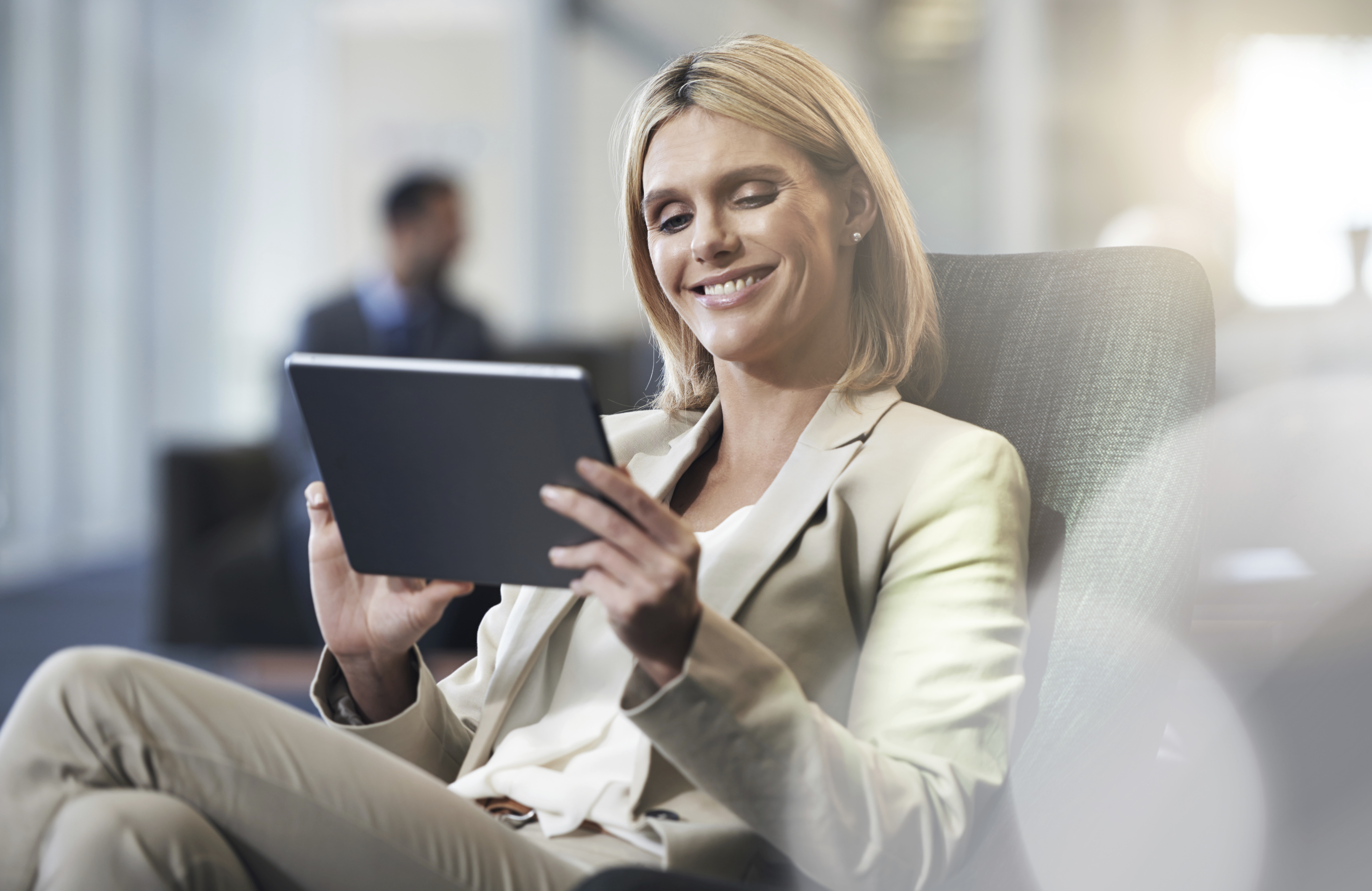 photo of female-presenting person in business attire smiling at tablet